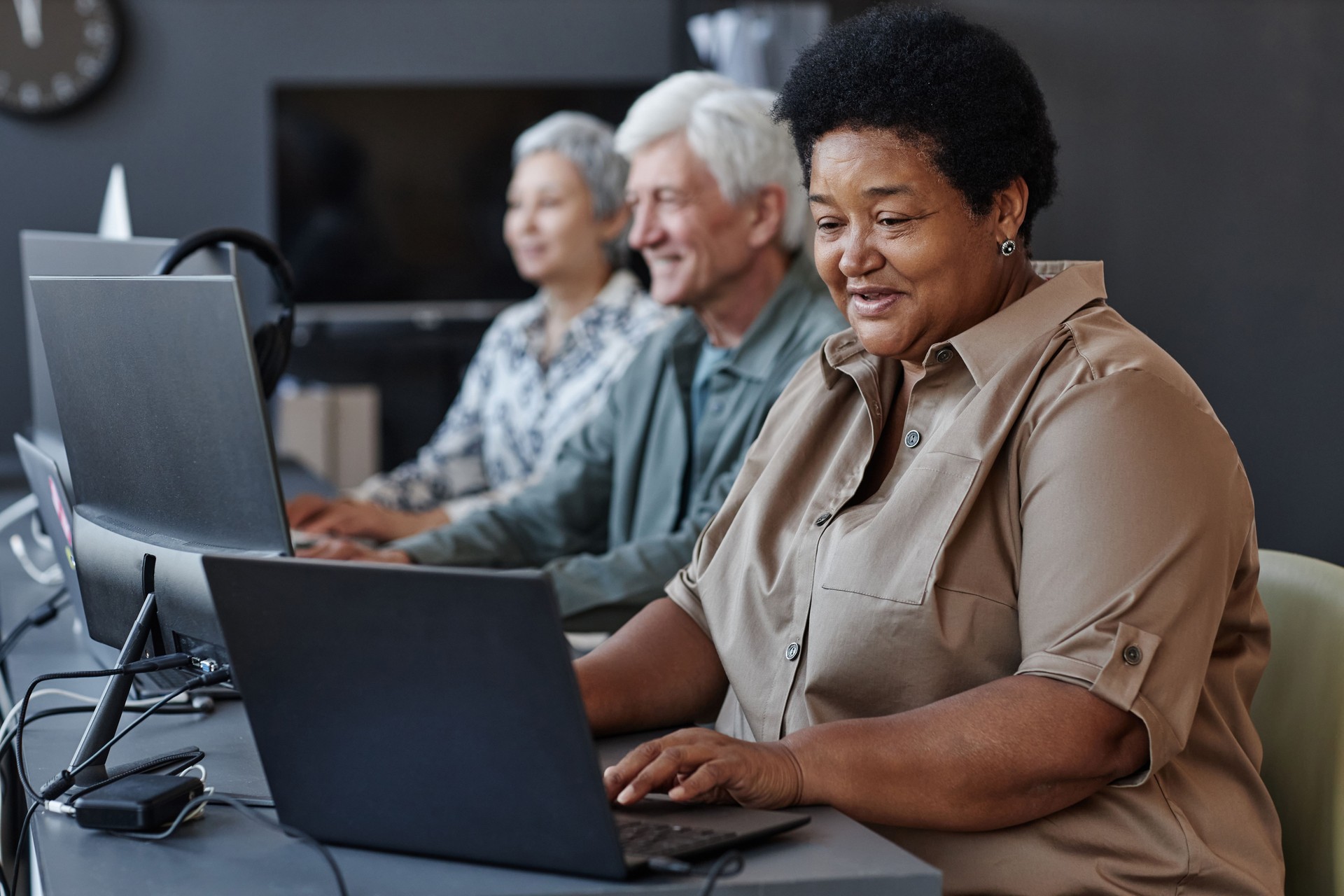 Senior black woman using computer and smiling in computer class for elderly